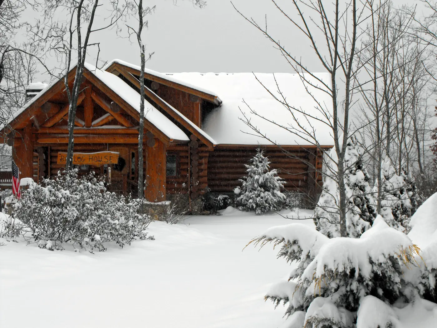 Log home with gabled roofs surrounded by fresh snow and snow-covered evergreens